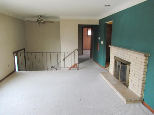 unfurnished living room with light colored carpet, a brick fireplace, and ceiling fan