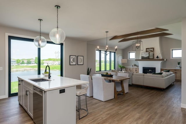 kitchen featuring vaulted ceiling with beams, a kitchen island with sink, sink, and pendant lighting