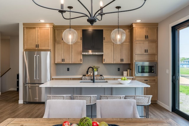 kitchen featuring decorative light fixtures, stainless steel appliances, tasteful backsplash, and an island with sink