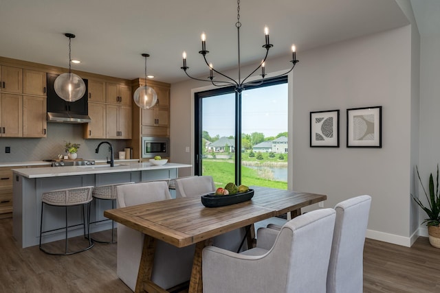 dining space featuring sink, dark wood-type flooring, and an inviting chandelier