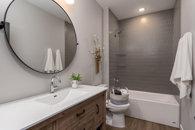 full bathroom with hardwood / wood-style floors, vanity, toilet, and tiled shower / bath