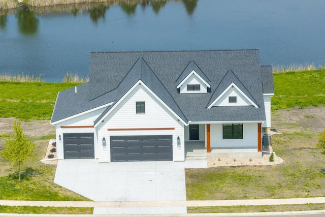 view of front facade with a porch, a garage, a water view, and a front lawn