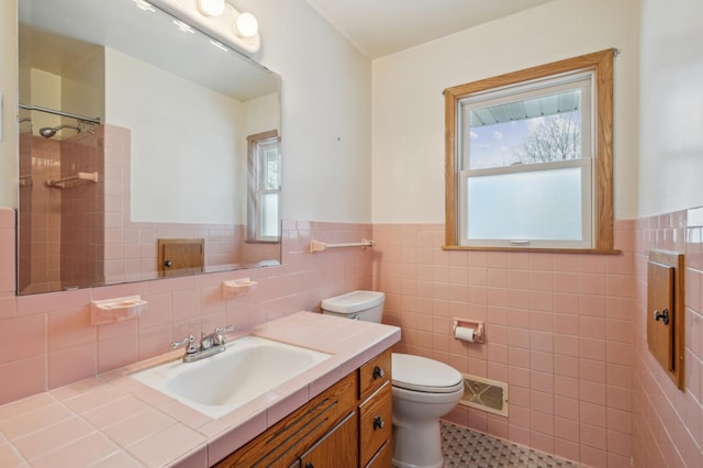 bathroom with a tile shower, toilet, a wealth of natural light, and tile walls