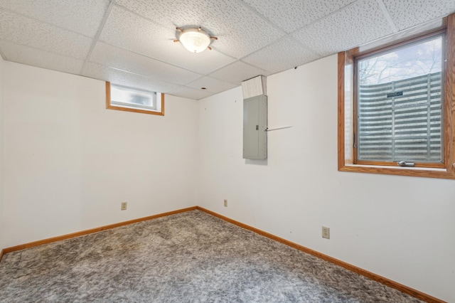 basement with a paneled ceiling, a wealth of natural light, and electric panel