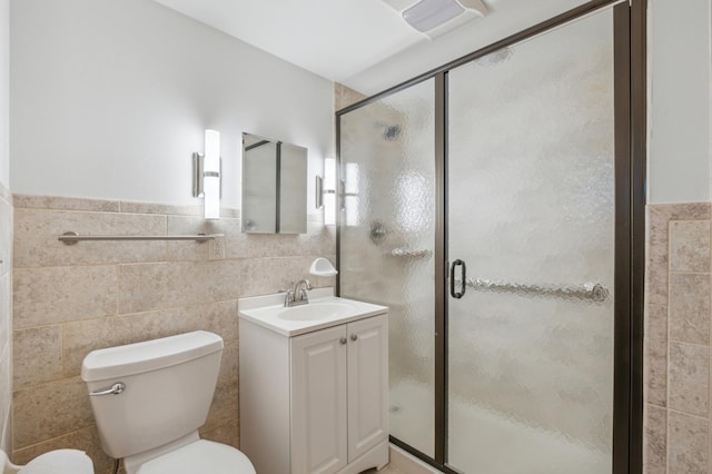 bathroom featuring vanity, toilet, a shower with shower door, and tile walls