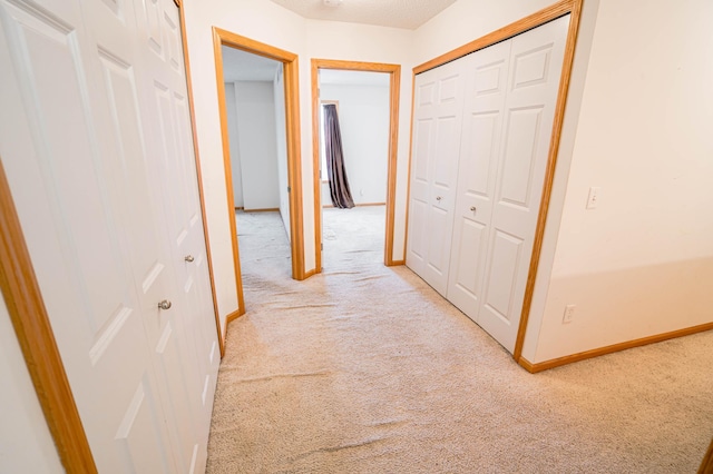 corridor featuring light colored carpet