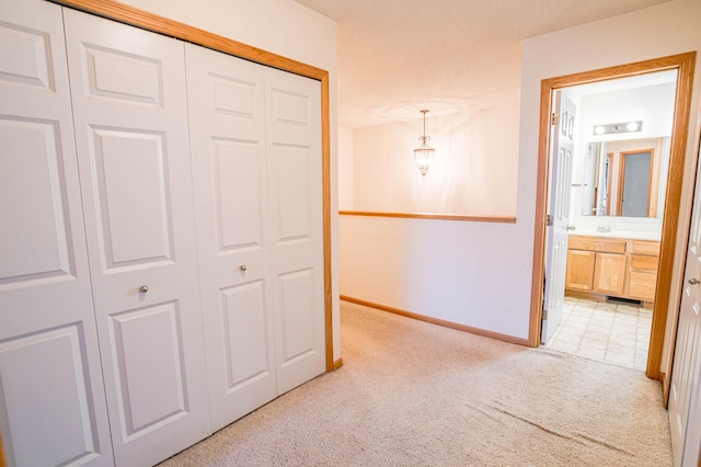 unfurnished bedroom featuring ensuite bathroom, light colored carpet, and a closet