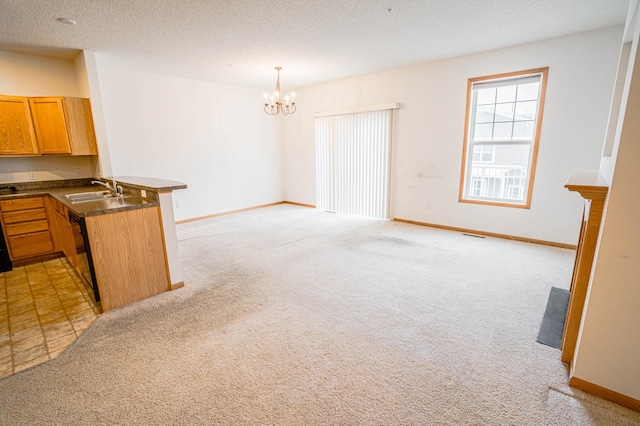 interior space featuring sink, a chandelier, hanging light fixtures, light colored carpet, and kitchen peninsula