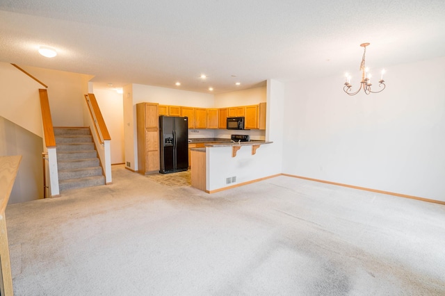 kitchen featuring a kitchen bar, decorative light fixtures, light carpet, kitchen peninsula, and black appliances