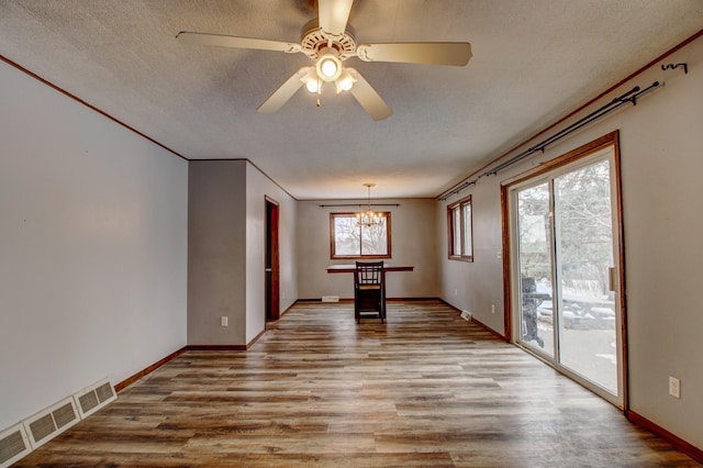 spare room featuring a textured ceiling, light wood-type flooring, and ceiling fan with notable chandelier