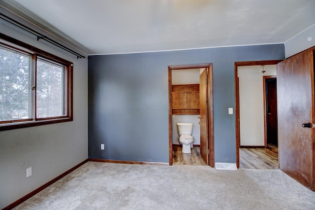 unfurnished bedroom with ensuite bath and light carpet