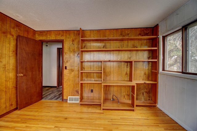 living room featuring a textured ceiling, wood walls, and wood-type flooring