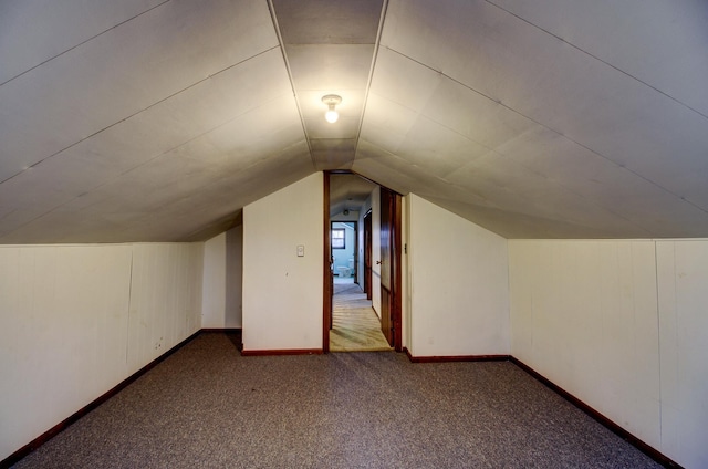 bonus room featuring vaulted ceiling and dark carpet