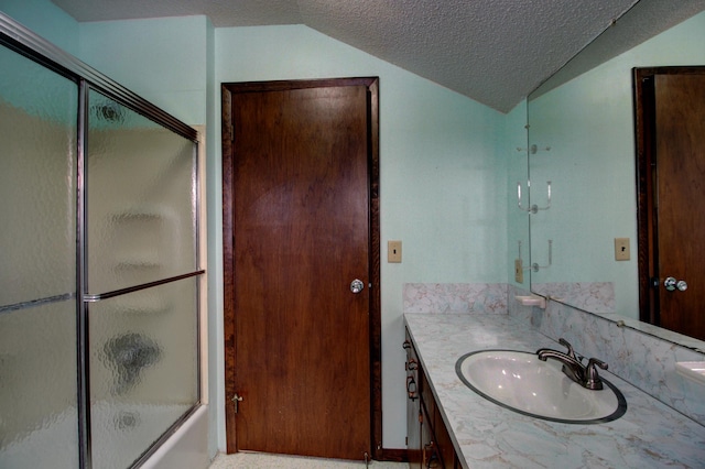 bathroom with lofted ceiling, a textured ceiling, vanity, and combined bath / shower with glass door