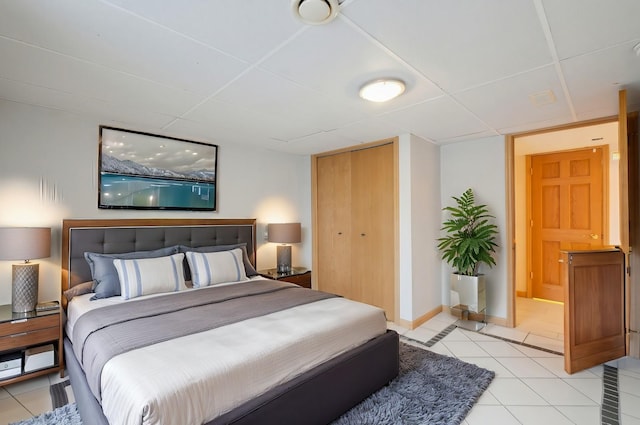 tiled bedroom with a closet and a drop ceiling