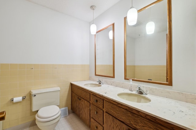 bathroom with vanity, tile walls, and toilet