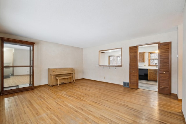 unfurnished room featuring sink, built in desk, and light wood-type flooring