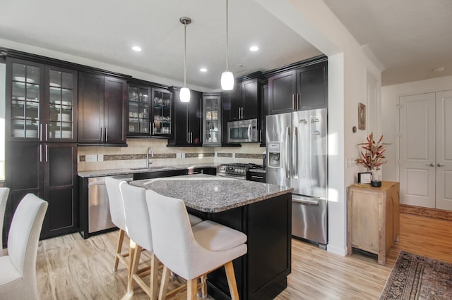 kitchen featuring light stone countertops, stainless steel appliances, sink, decorative light fixtures, and a center island