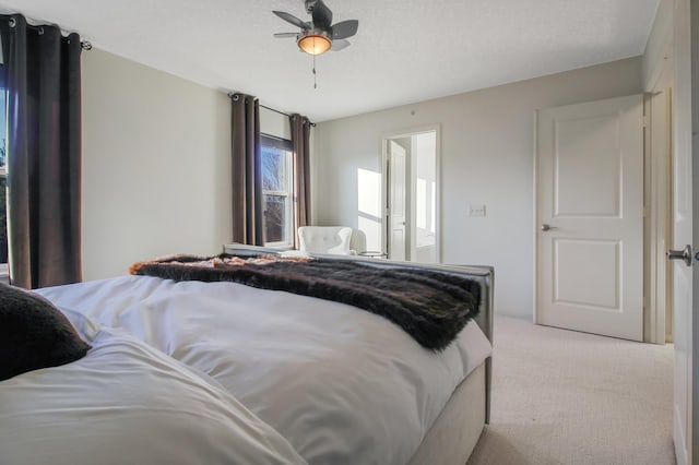 bedroom featuring a textured ceiling, ceiling fan, and light carpet