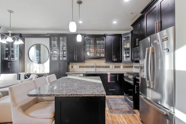 kitchen featuring sink, decorative light fixtures, a breakfast bar, a kitchen island, and appliances with stainless steel finishes