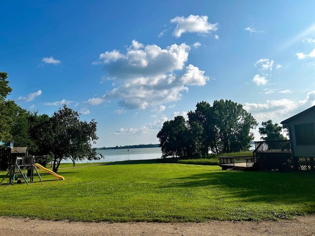 surrounding community with a deck with water view, a playground, and a lawn