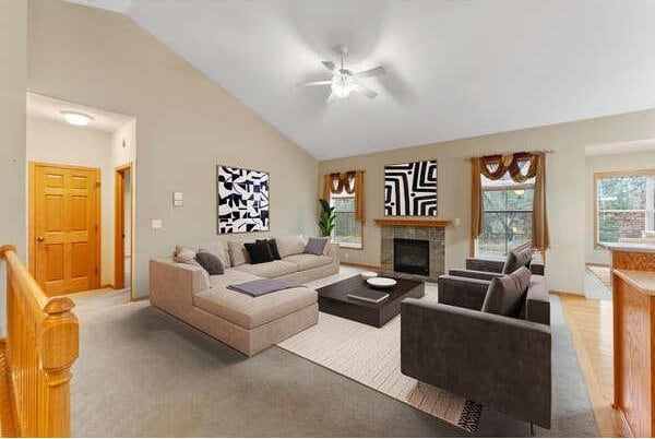 carpeted living room featuring a fireplace, high vaulted ceiling, and ceiling fan