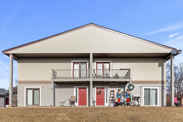 back of property featuring a balcony and a yard