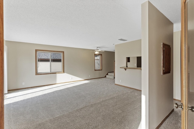 spare room featuring ceiling fan, light colored carpet, and a textured ceiling