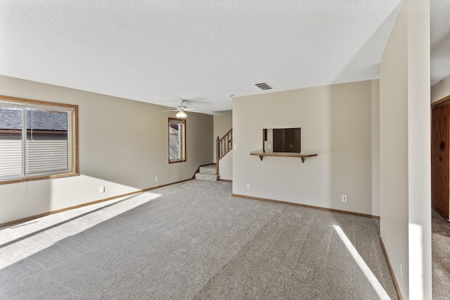 unfurnished living room featuring a textured ceiling, ceiling fan, plenty of natural light, and light carpet