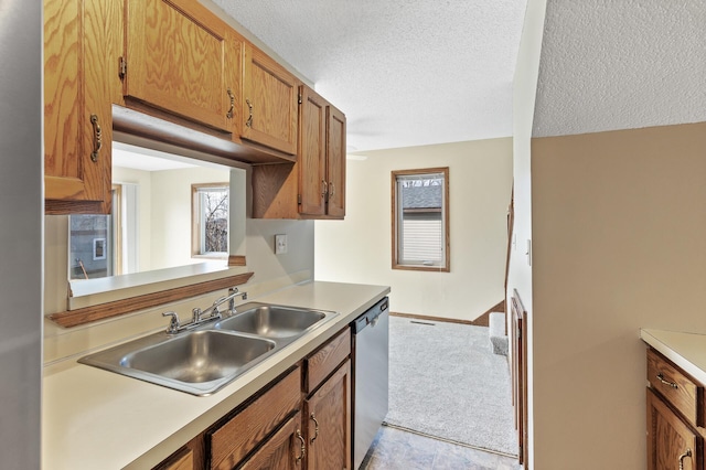 kitchen featuring a wealth of natural light, sink, stainless steel dishwasher, and a textured ceiling