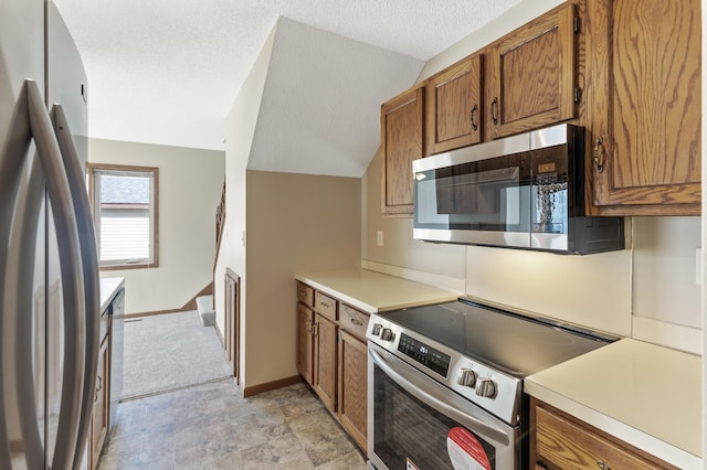 kitchen featuring appliances with stainless steel finishes, a textured ceiling, and lofted ceiling