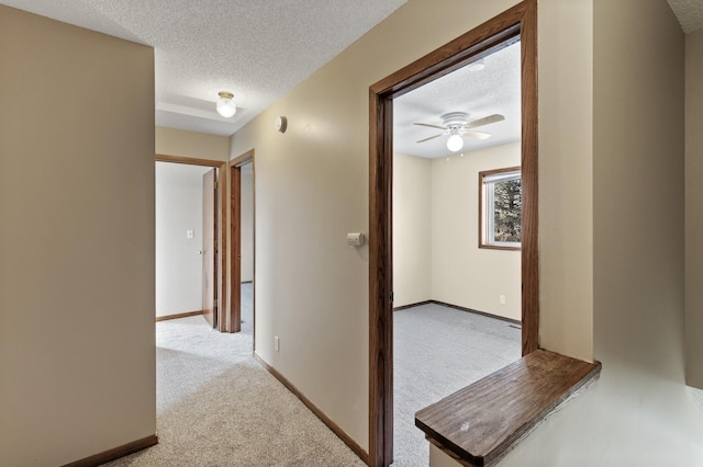 corridor featuring light colored carpet and a textured ceiling