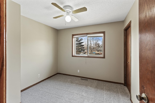 empty room featuring a textured ceiling, ceiling fan, and light carpet