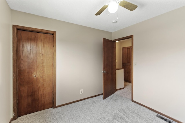 unfurnished bedroom with ceiling fan, light colored carpet, and a closet