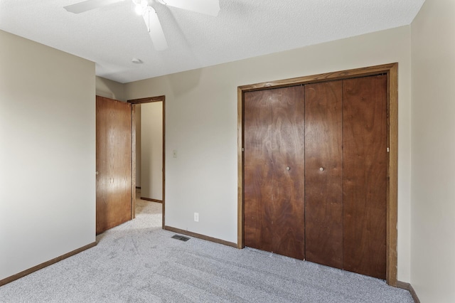 unfurnished bedroom with ceiling fan, a closet, light carpet, and a textured ceiling