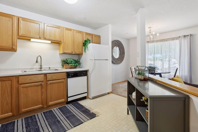 kitchen with a textured ceiling, white appliances, sink, and a chandelier