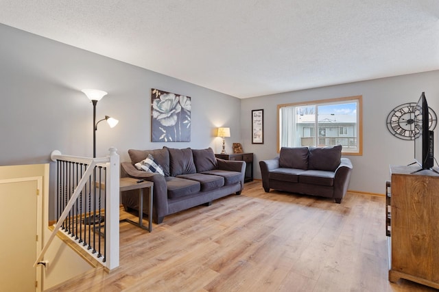 living room featuring light wood-type flooring and a textured ceiling