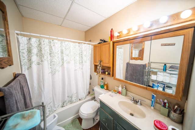 full bathroom featuring a drop ceiling, vanity, toilet, and shower / bathtub combination with curtain