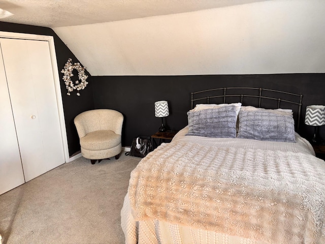 bedroom featuring lofted ceiling, carpet floors, and a textured ceiling