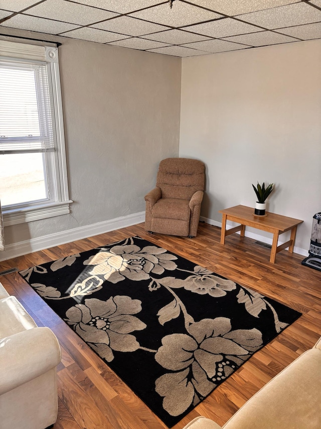 living area featuring a paneled ceiling and wood-type flooring