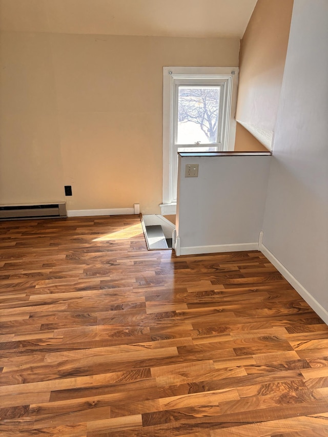 empty room featuring hardwood / wood-style flooring and baseboard heating