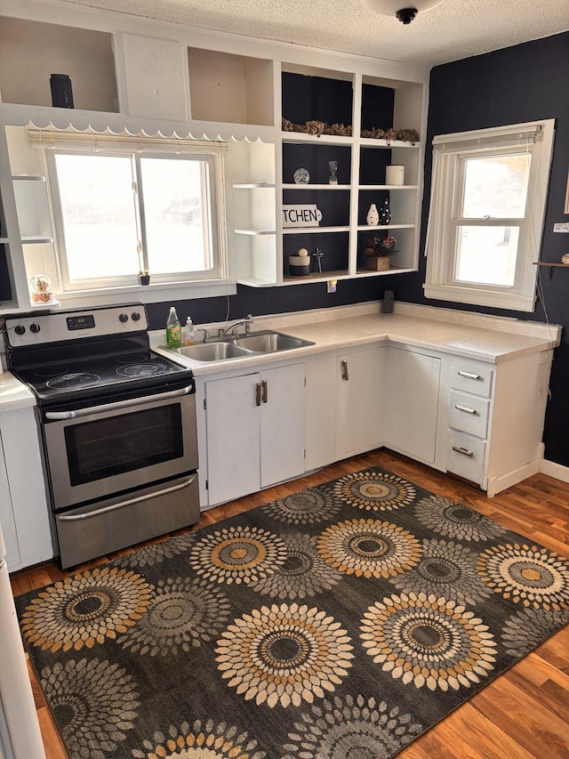 kitchen with open shelves, wood finished floors, a sink, and stainless steel range with electric cooktop