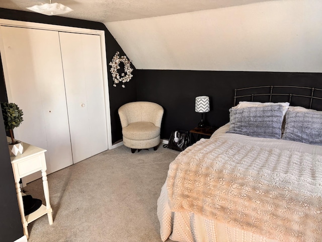 bedroom with carpet floors, lofted ceiling, a closet, and a textured ceiling