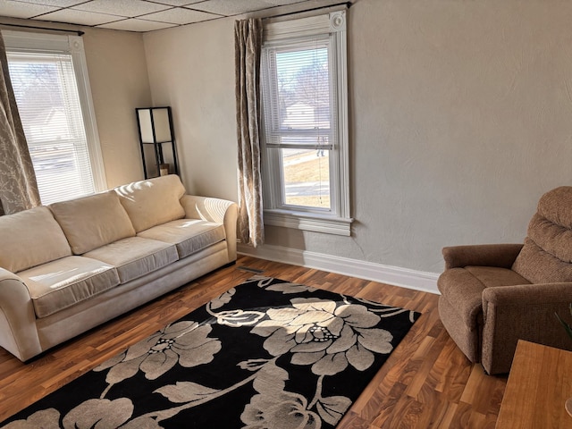 living room with a healthy amount of sunlight, baseboards, a paneled ceiling, and wood finished floors