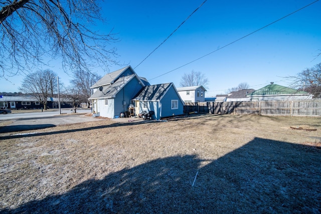 view of yard featuring an outdoor structure, fence, and a residential view