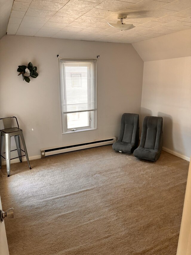 unfurnished room featuring a baseboard heating unit, lofted ceiling, baseboards, and carpet