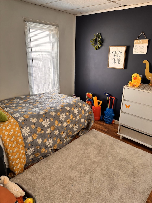 bedroom with wood finished floors and a paneled ceiling