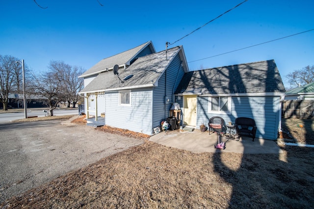 rear view of house featuring a shingled roof and a patio