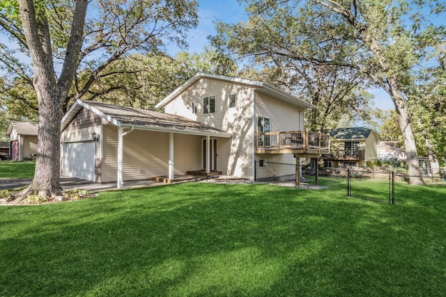 back of property featuring a lawn, a garage, and a wooden deck