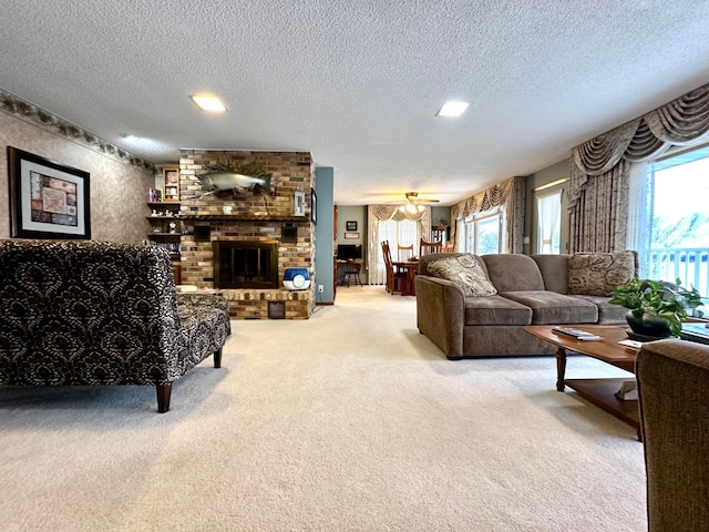 living room featuring ceiling fan, a fireplace, carpet, and a textured ceiling